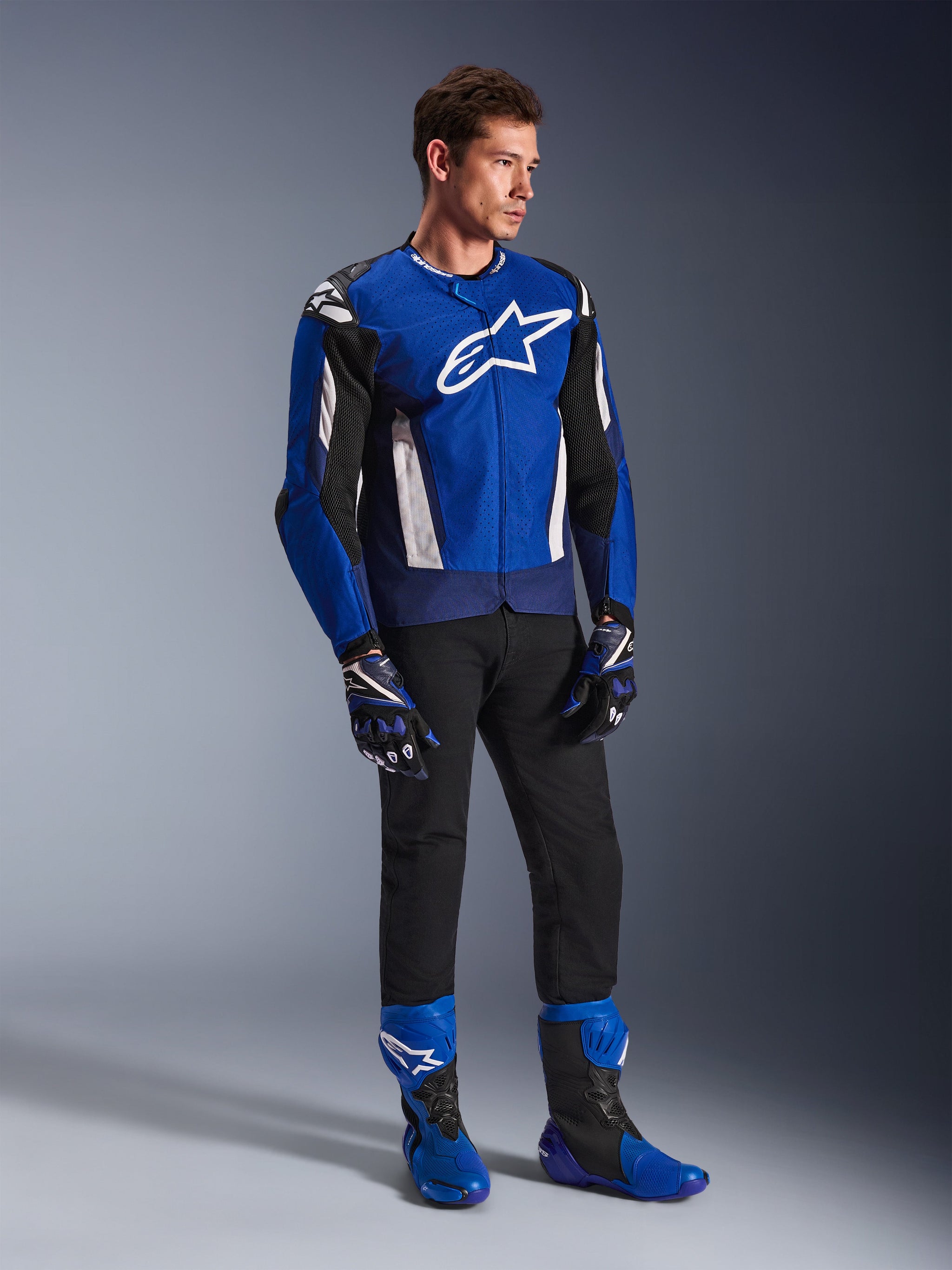 Alpinestars T-GP Air Jacket, Sport Textile Motorcycle Jacket, Bright Blue Navy and White, worn with matching blue and black gloves, black pants, and blue racing boots, featuring white chest logo and technical mesh panels, full-body studio shot