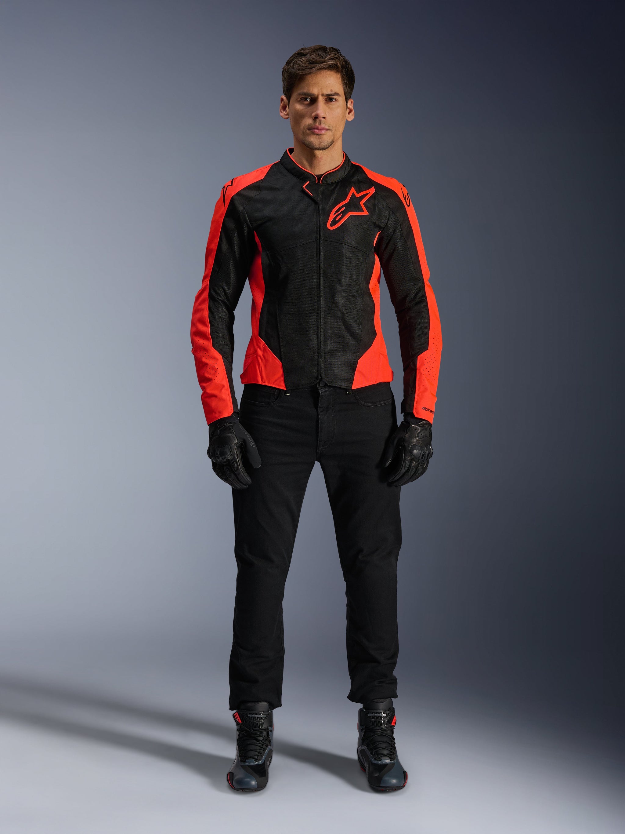 Male model wearing the Alpinestars Viper Air V4 Jacket in Red Fluo and Black, paired with black riding pants, gloves, and boots, featuring breathable mesh panels for ventilation and a bold star logo on the chest, sporty motorcycle road apparel