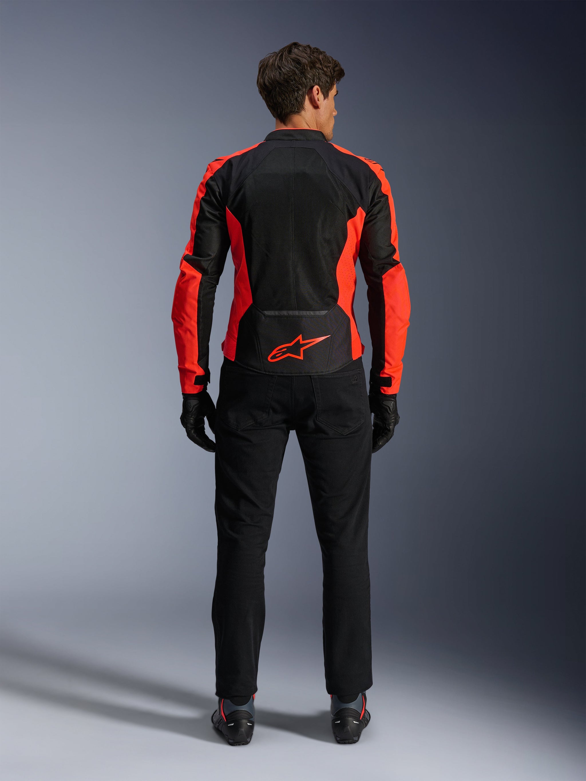 Alpinestars Viper Air V4 Jacket, Red Fluo and Black, back view showing large tech mesh panels and bright red fluorescent side accents, red Alpinestars logo on the lower back, worn with black riding pants and gloves.