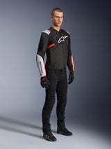 Alpinestars T-Sps Air V2 Jacket, Black White Red Fluo, worn by a male model with black riding pants and gloves, textile motorcycle jacket featuring large mesh panels, white shoulder and forearm sections, and bold Alpinestars logo on the chest.
