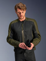 Man wearing the Alpinestars C-1 Air Jacket in Khaki, urban motorcycle jacket with olive green textile and black mesh panels, looking down while holding black motorcycle gloves, clean and contemporary style for road riding.