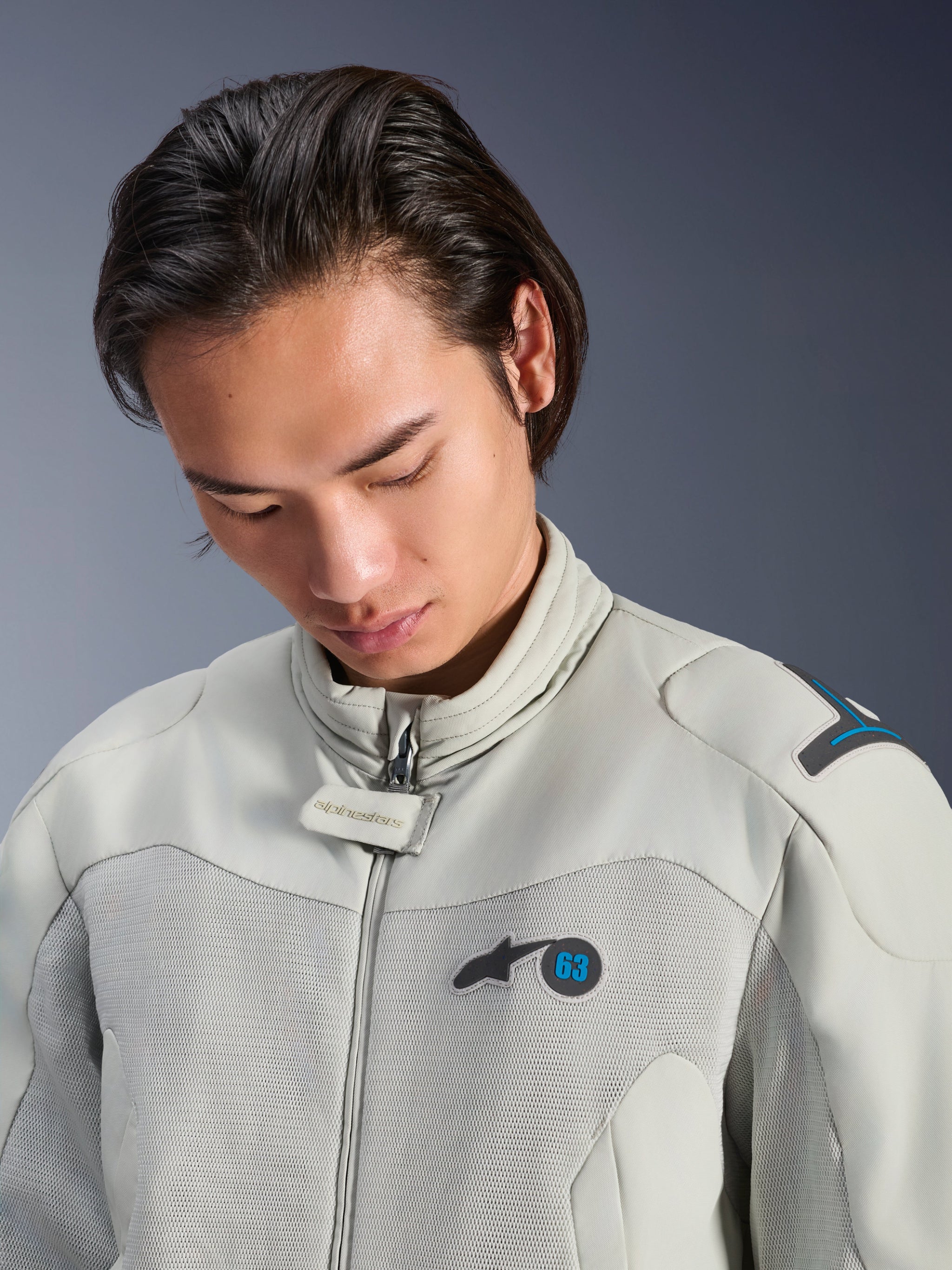 Male model wearing the Alpinestars Circal-1 Air Jacket in Metal Gray with Methyl Blue accents, close-up view highlighting the collar, mesh chest panels, and minimalist logo branding, sustainable urban motorcycle gear.