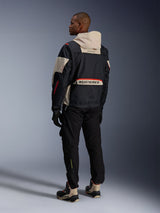 Rear view of a man wearing Alpinestars Acteon Pants in Black, paired with a Mogress Air Jacket in black and cream, black gloves, and riding boots, contemporary urban motorcycle outfit