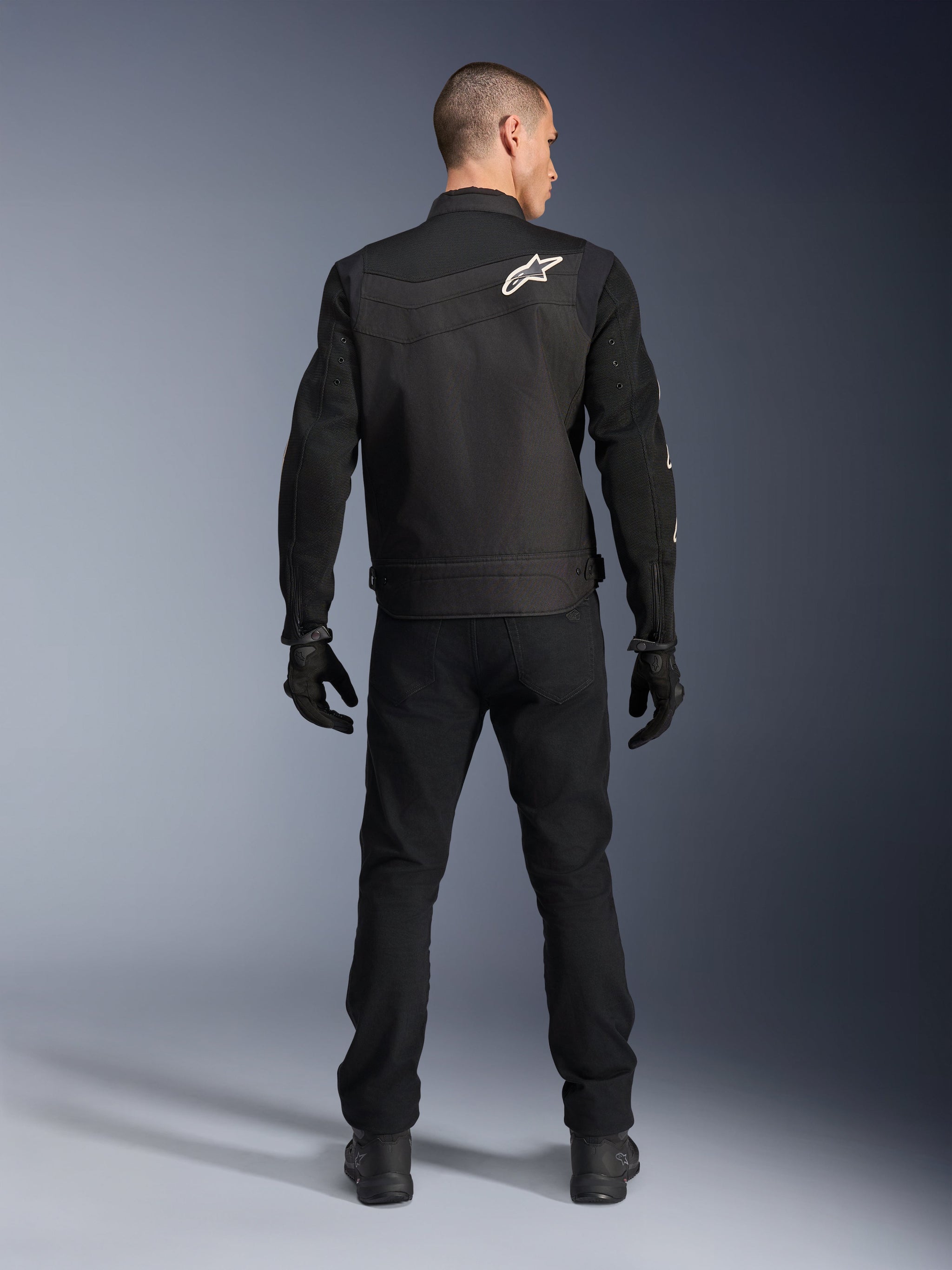 Alpinestars T-Dyno Air Jacket, Black, Rear view on model, Textile motorcycle jacket featuring 3D mesh panels and a white star logo on the shoulder, worn with black pants and gloves, modern urban riding outfit