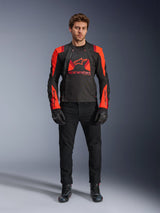 Alpinestars T-Stunt Air Jacket, Black Red Fluo and Dark Red, worn by a model with black riding jeans and gloves, featuring a modular 2-in-1 design with prominent mesh panels for airflow, sport-cut motorcycle gear for road riding