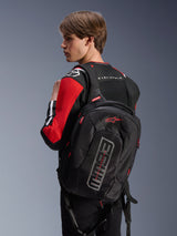 Alpinestars MM93 City Hunter V2 Backpack, Black, featuring red Astars logo and grey MM93 branding, worn by a rider in a red and black motorcycle jacket, urban riding gear from the Marc Márquez collection