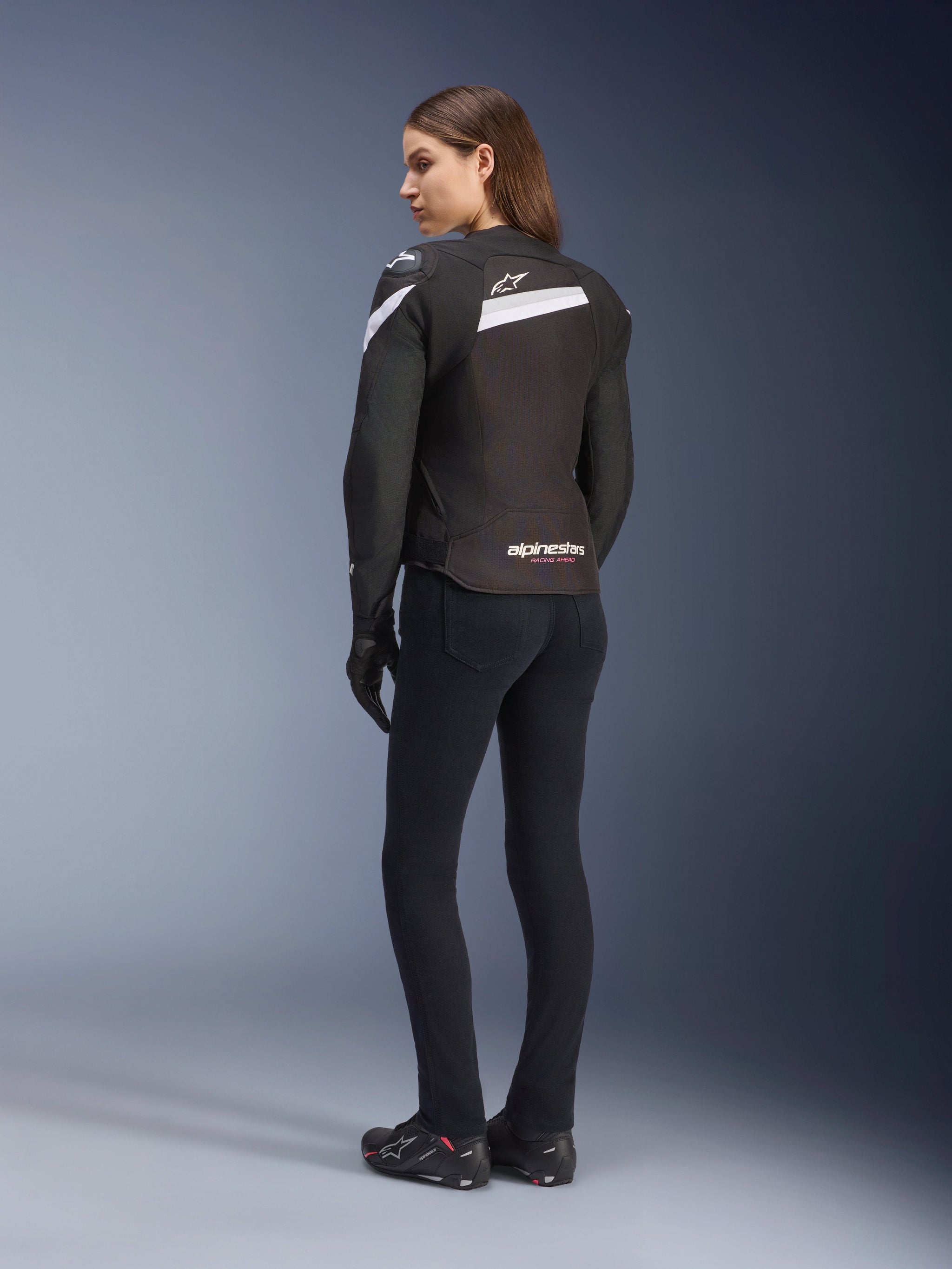 Alpinestars Stella T-GP Plus R V4 Jacket, Women's Textile Motorcycle Jacket, Black and White, back view on model, featuring white shoulder accents and Alpinestars logo, worn with black pants and riding gloves, sport-fit design for road riding