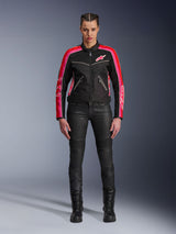Female rider wearing the Alpinestars Stella T-Dyno Air Jacket, Black with Bright Red and Fuchsia accents, paired with black motorcycle pants and lace-up boots, featuring 3D mesh panels, tailored fit, and pink star logos, urban riding gear outfit
