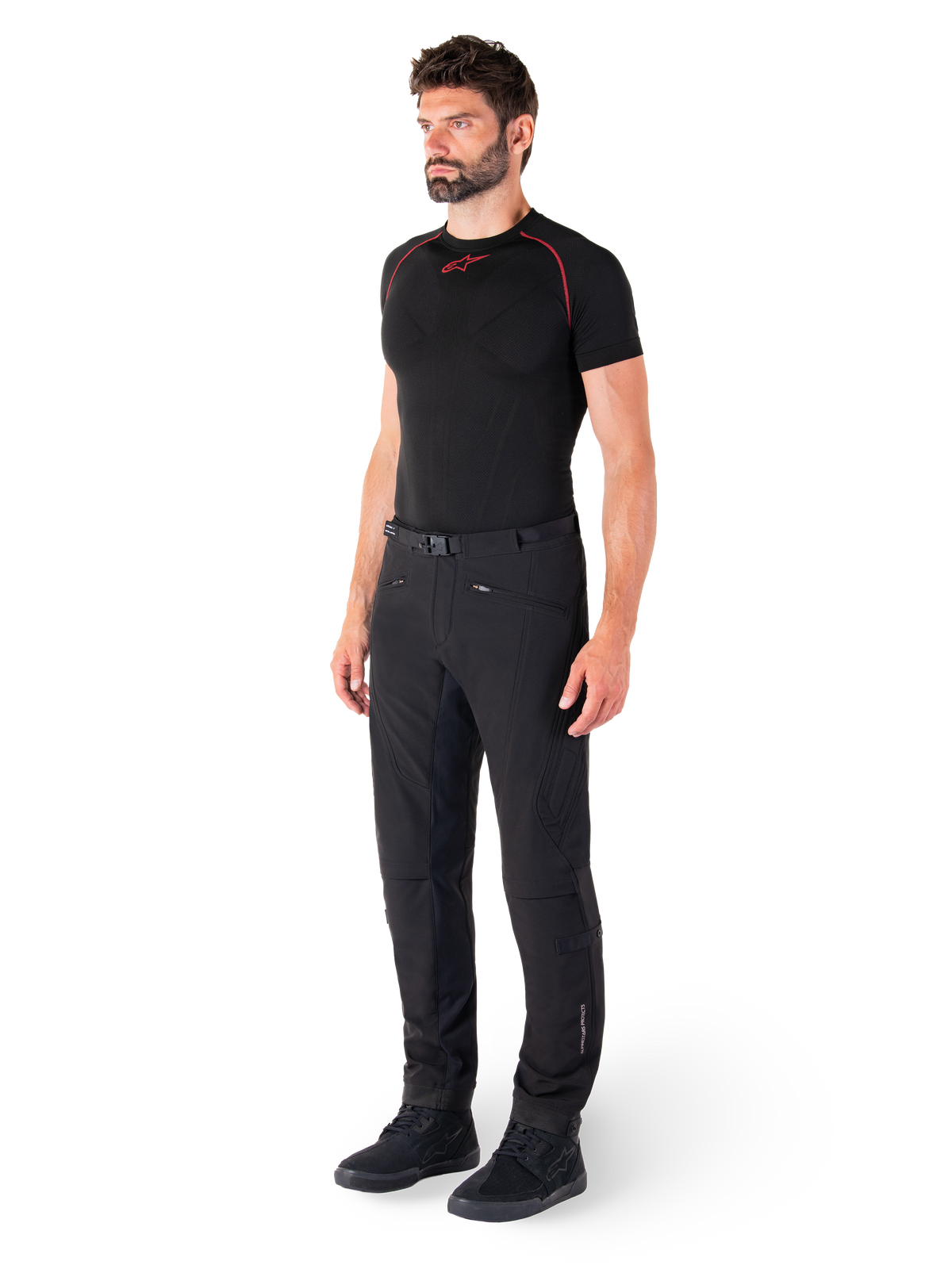 Alpinestars Alden Pants, Urban Motorcycle Pants, Black, regular fit softshell textile, worn by a model with a black base layer and riding shoes, featuring a waist belt with magnetic closure and zippered pockets.