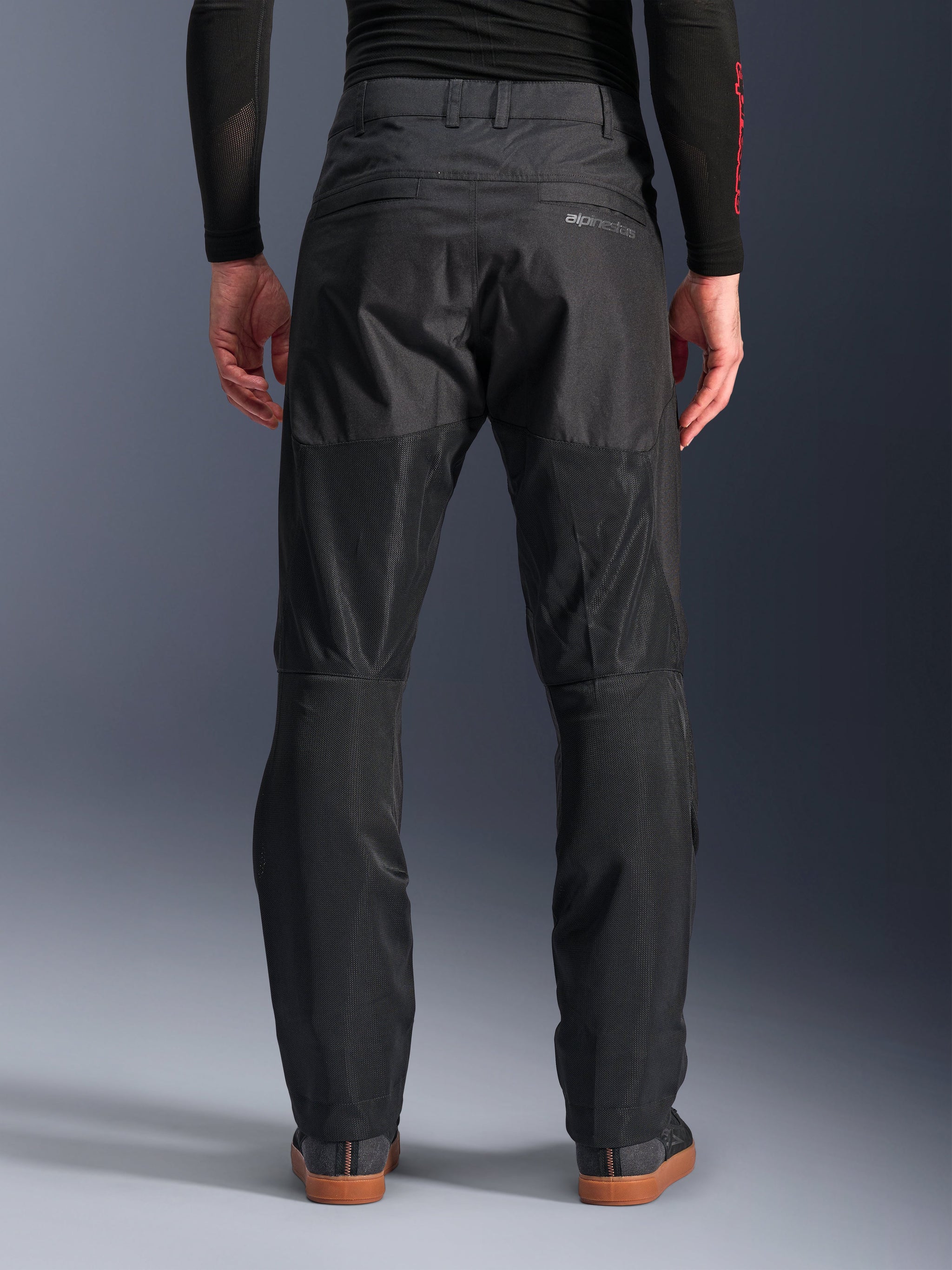 Alpinestars C-1 Air Pants, back view, Black, urban textile motorcycle pants featuring large tech mesh panels on the back of the legs for ventilation, clean design with subtle branding, worn with a black base layer and casual riding shoes.