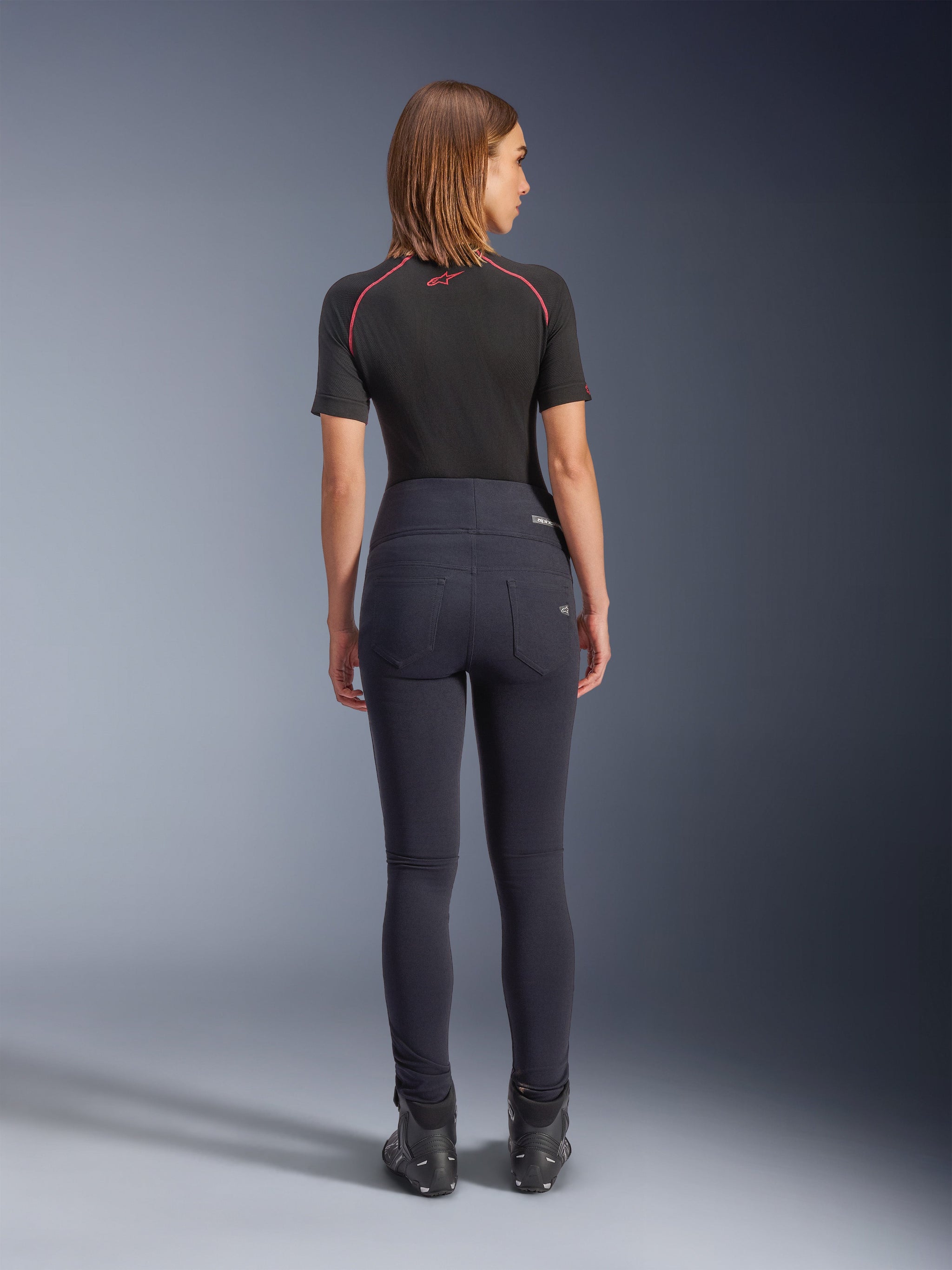 Alpinestars Stella Flex-AST Leggings in Black, women's high-waisted motorcycle pants, back view showing skinny fit and rear pockets, worn with black short-sleeve top and riding boots, urban riding gear