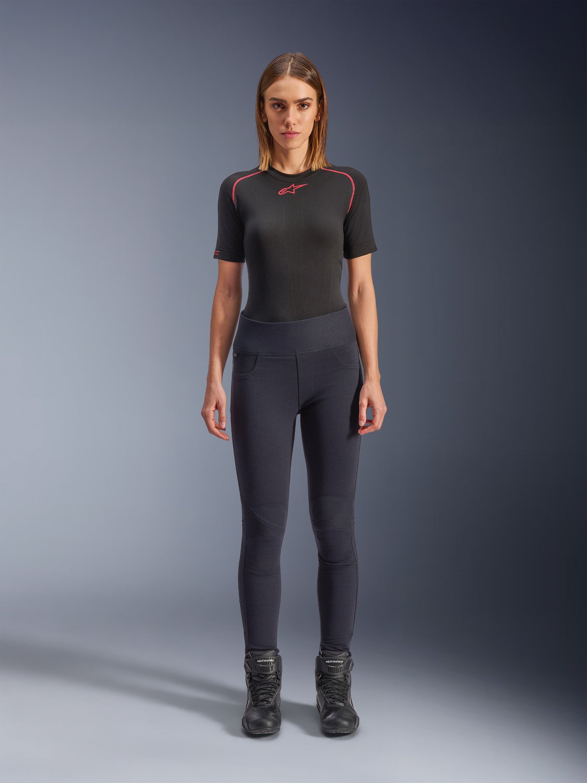 Alpinestars Stella Flex-Ast Leggings, Woman's Motorcycle Leggings, Black, worn with a black short-sleeved top with red details and black riding boots, slim-fit contemporary urban riding gear, front view