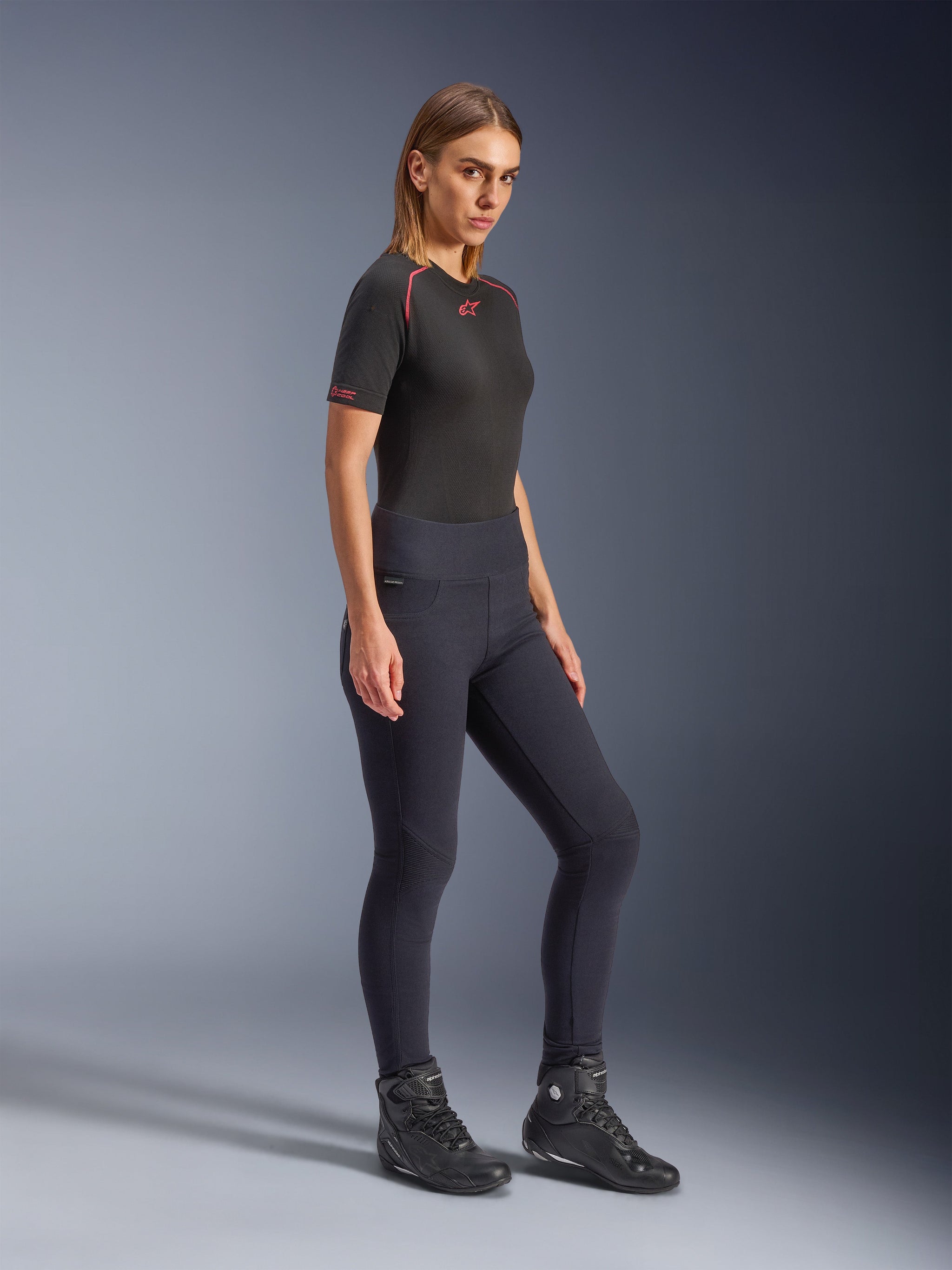 Alpinestars Stella Flex-Ast Leggings, Women's Motorcycle Leggings in Black, high-waisted slim fit design, worn with a black t-shirt featuring red accents and black riding boots, studio full-body shot