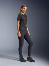 Model wearing Alpinestars Woman Stella Flex-AST Leggings in black, high-waisted skinny fit with accordion knee panels, paired with a black Alpinestars short-sleeve top and black motorcycle boots, full-body studio shot.