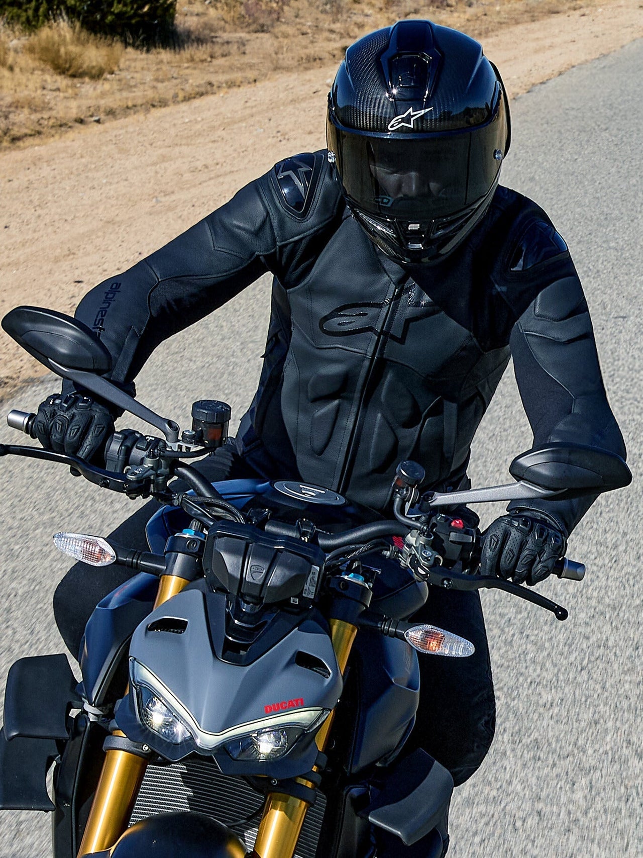 Alpinestars Dusk Leather Jacket, Black men's road racing leather jacket with shoulder sliders, riding a grey Ducati.