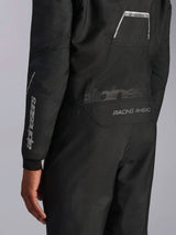 Close-up of Alpinestars Hypertech V3 Suit in Black/Dark Shadow, showing back graphics 'RACING AHEAD' and 'HYPERTECH V3', with white logo branding on the sleeve, professional auto racing gear.
