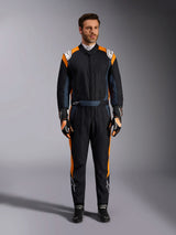 Alpinestars GP Pro Comp V2 FIA Suit, Black Asphalt and Orange Fluo auto racing suit, male model wearing full protective gear with matching racing gloves and shoes, features white Alpinestars logos and vibrant orange side panels, professional motorsport apparel