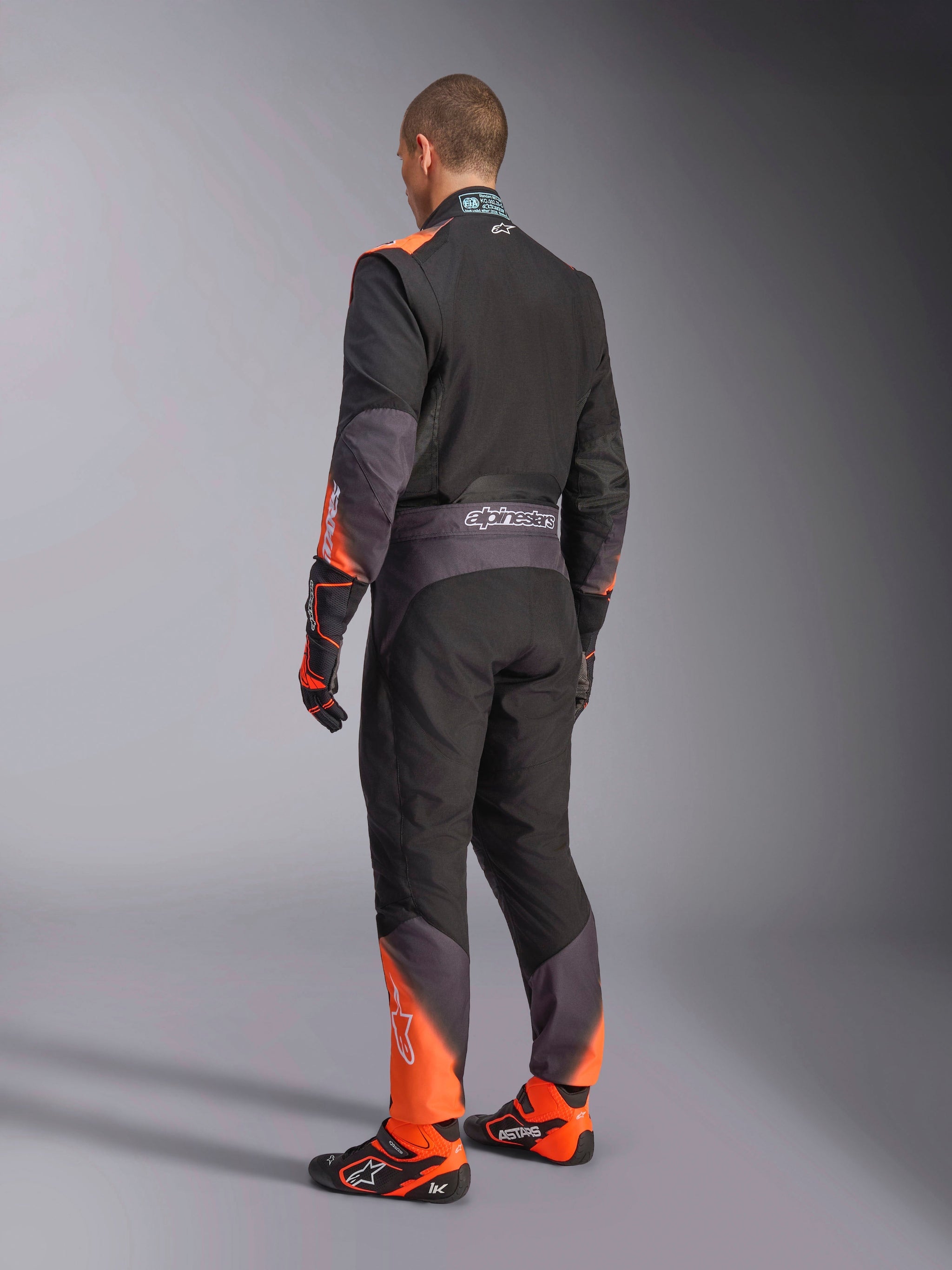 Alpinestars KMX-5 V3 Karting Suit, Men's rear view in black and orange fluo, FIA 8877-2022 Grade 1 certified.