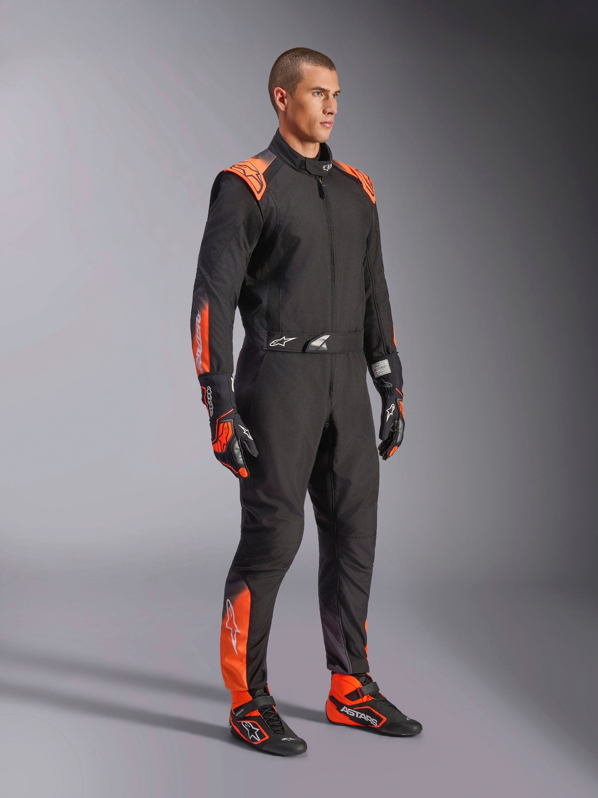 Alpinestars KMX-5 V3 Karting Suit, Men's Black and Orange Fluo, FIA Grade 1 textile racing one-piece worn by a model.