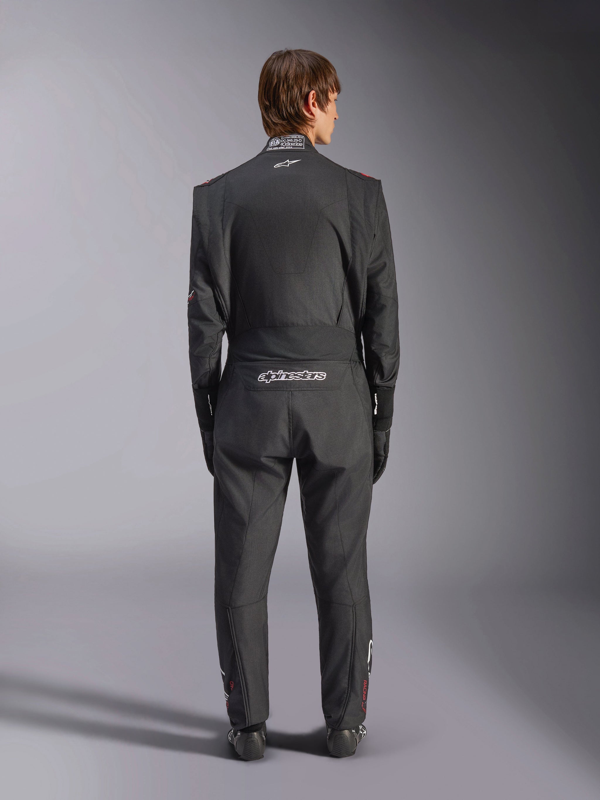 Alpinestars GP Tech V4 Suit, Auto Racing Suit, Black and White, back view featuring white Alpinestars branding and FIA certification on the collar, sleek ergonomic fit for professional driver protection
