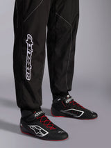 Alpinestars KMX-9 V3 Suit, Karting Suit, Black and White, lower leg view showing large white Alpinestars branding, worn with black and red racing boots, professional motorsport gear for karting