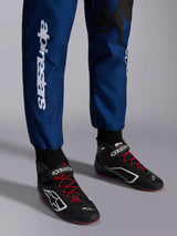 Alpinestars KMX-9 V3 Graphic 5 Suit, Navy Red, close-up of lower legs and karting shoes, navy blue fabric with white vertical Alpinestars branding, black shoes with red laces and white logos, professional karting gear