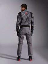 Alpinestars KMX-9 V3 Graphic 5 Suit, Karting Suit, Dark Gray and Black camouflage pattern on the upper body, back view showing stretch panels and Alpinestars branding, worn with black gloves and black racing shoes with red details, professional motorsport racing gear