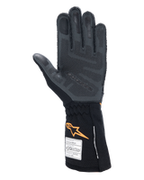 Alpinestars Tech-1 ZX V4 Gloves, Auto Racing Gloves, Black and Orange Fluo, palm view showing 3D silicone grip patterning and honeycomb texture, FIA and SFI homologation labels visible on the cuff, professional motorsport gear