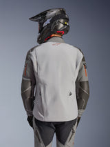 Alpinestars Nazca 3L GORE-TEX PRO Jacket, Adventure Motorcycle Jacket, Back View, Dark Gray and Mid Gray, features Superfabric reinforcements on elbows and shoulders, red logo on the back, worn with matching adventure gear and a carbon fiber helmet.