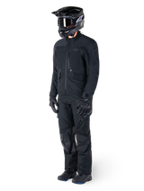 Motorcyclist wearing the Alpinestars St-7 Prime GORE-TEX Jacket in black, coordinated adventure touring outfit with matching black pants, black helmet with goggles, and gloves, featuring a streamlined and functional design for all-weather performance.