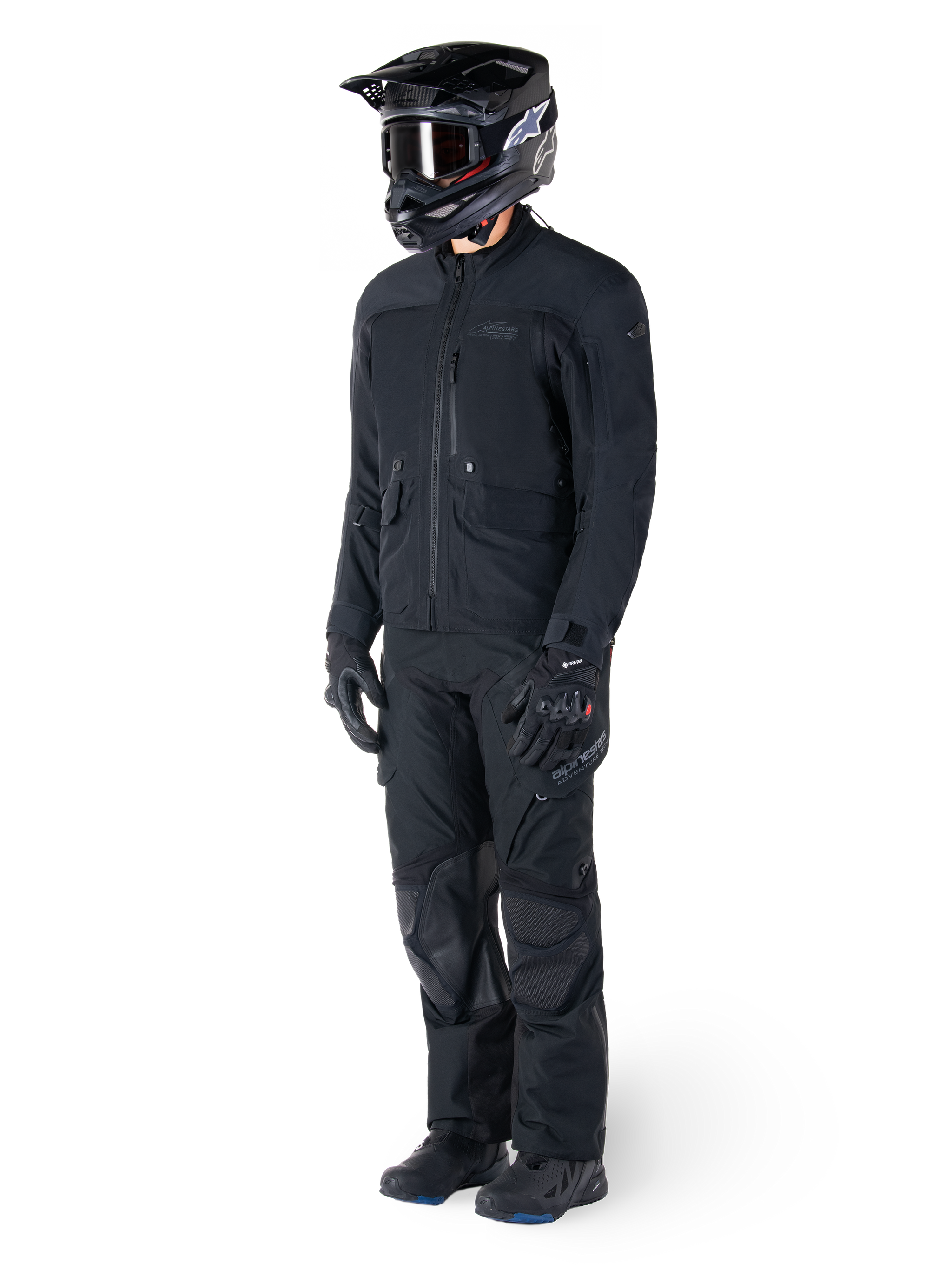 Motorcyclist wearing the Alpinestars St-7 Prime GORE-TEX Jacket in black, coordinated adventure touring outfit with matching black pants, black helmet with goggles, and gloves, featuring a streamlined and functional design for all-weather performance.