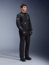 Alpinestars ST-7 2L GORE-TEX Pants, worn by a model with the matching ST-7 Jacket, all-black adventure touring motorcycle outfit, featuring GORE-TEX branding, cargo pockets, and black gloves and boots, studio shot against a gray background