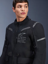 Alpinestars ST-7 2L GORE-TEX Jacket, Motorcycle Jacket, Black and Dark Gray, worn by a male model, featuring Alpinestars Exploration Equipment branding on the chest, reflective gray accents, and adventure-ready textile construction