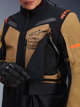 Alpinestars ST-7 2L GORE-TEX Jacket, Adventure Touring Motorcycle Jacket, Gobi Brown and Black, close-up showing the unzipped chest ventilation panel revealing breathable mesh, featuring Alpinestars Exploration Equipment branding and orange accents.