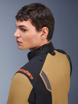 Alpinestars ST-7 2L GORE-TEX Jacket, Motorcycle Jacket, Gobi Brown and Black, side profile view of a man wearing the jacket, featuring orange branding on the shoulder, a high collar with shock cord adjustment, and Tech-Air branding.