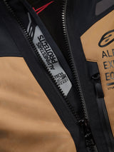 Close-up detail of Alpinestars ST-7 2L GORE-TEX Jacket in Gobi Brown and Black, featuring the 'ALPINESTARS PROTECTS' and 'TECH-AIR READY' branding inside the main zipper, showcasing rugged textile construction and chest logos