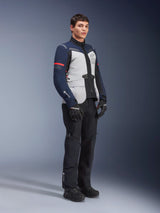 Alpinestars ST-7 2L GORE-TEX Jacket in Ice Gray, Dark Blue, and Black colorway with red accents, worn by a male model with black motorcycle pants and gloves, professional adventure touring motorcycle gear