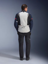 Alpinestars ST-7 2L GORE-TEX Jacket, Rear view of a rider wearing an adventure touring motorcycle jacket in Ice Gray, Dark Blue, and Black, featuring a large back panel with the Alpinestars logo and matching black pants, designed for all-weather riding.