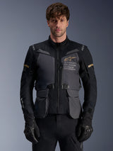 Alpinestars ST-7 2L GORE-TEX Jacket, Men's Adventure Touring Motorcycle Jacket, Deep Gray and Black with Khaki accents, featuring 'Alpinestars Exploration Equipment' branding, waterproof cargo pockets, and high collar, worn by a model with black gloves
