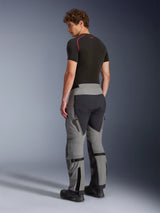 Alpinestars Nazca 3L GORE-TEX PRO Pants, adventure riding pants, dark gray and black, back view of a model wearing technical adventure gear, showing rear stretch panels, ventilation details, and lower leg volume adjusters.
