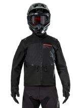 Alpinestars Pro-Dura Jacket, Black Off-road Motorcycle Jacket, front view worn by a rider with a matching black helmet and goggles, featuring red Alpinestars branding, zippered chest pockets, and durable textile construction for enduro riding.