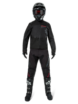 Alpinestars Pro-Dura Jacket, Black Off-Road Enduro Jacket, shown on a model with a complete gear set including a black helmet with red goggles, black pants with red accents, black and white boots, and black gloves, rally-inspired rugged design for trail riding