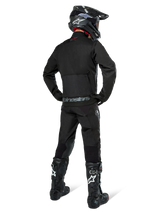 Alpinestars Pro-Dura Jacket, Black Off-road Enduro Jacket, rear view worn with matching pants and black Tech 10 boots, featuring prominent Alpinestars branding on the lower back, rugged textile construction for aggressive trail riding