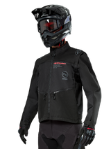 Alpinestars Pro-Dura Jacket, Off-Road Motorcycle Jacket, Black with red and grey branding, features zippered front pockets and high collar, worn with a black motocross helmet and gloves for enduro racing