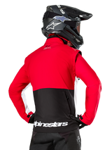Alpinestars Lite-Dura Softshell Jacket, Black Bright Red White, back view on a motocross rider, red upper body and sleeves with black lower back panel, zippered rear storage pocket, white Alpinestars logo on the bottom hem, worn with a black helmet and pants