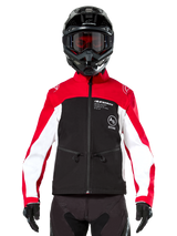Alpinestars Lite-Dura Softshell Jacket in Black Bright Red and White, worn by a motocross rider with a black helmet and red-tinted goggles, featuring white panels on the sleeves, Alpinestars branding on the chest, and a sporty off-road design.