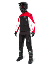 Motocross rider wearing the Alpinestars Lite-Dura Softshell Jacket in Black, Bright Red, and White, featuring a black body with red and white sleeves, paired with black pants, a black helmet with red goggles, and black and white boots, complete off-road racing outfit.
