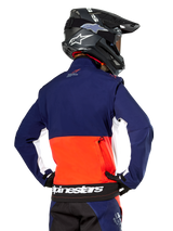 Alpinestars Lite-Dura Softshell Jacket, Navy Hot Orange and White, rear view worn by a motocross rider, featuring a large white logo on the back hem and zippered storage pocket, part of a complete off-road racing outfit.