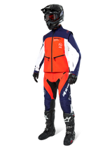 Motocross rider wearing the Alpinestars Lite-Dura Softshell Jacket in Navy Hot Orange and White, complete with matching off-road pants, black helmet with goggles, and black racing boots, coordinated enduro gear set