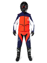 Motocross rider wearing complete off-road gear, Lite-Dura Softshell Jacket in Navy Hot Orange and White, matching navy and orange pants, black helmet with goggles, black and white boots, black gloves, coordinated outfit for enduro racing